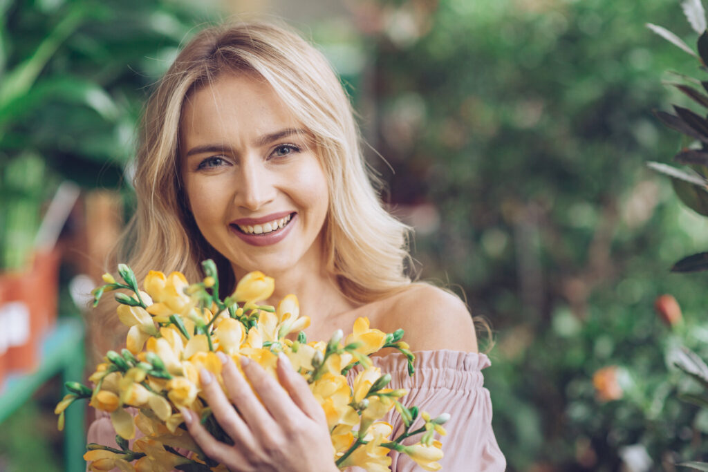 A happy woman standing with a yellow flower bouquet
