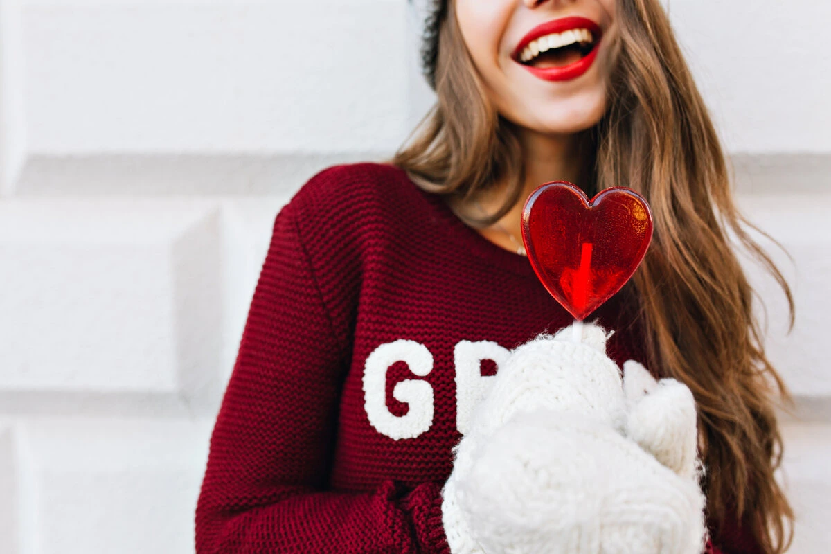 girl smiling holding a heart shape lollipop